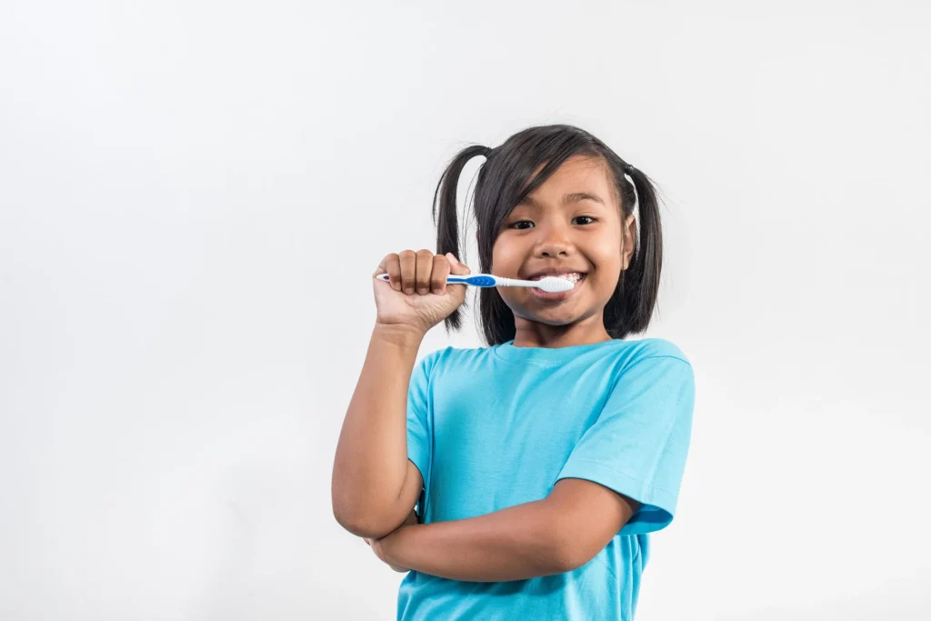 Criança de camisa azul escovando os dentes.