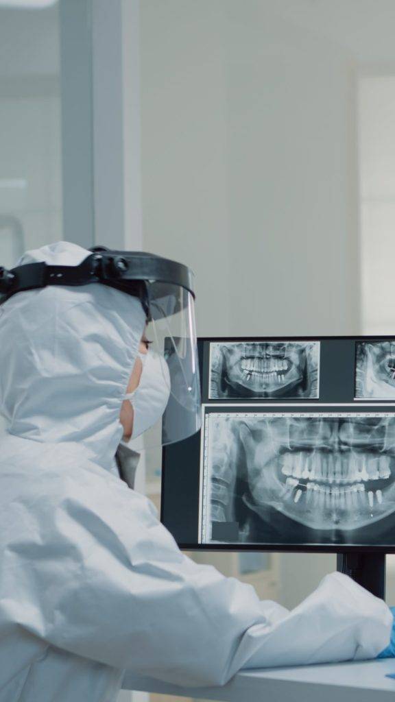 Dentista analisando uma radiografia odontológica em uma tela de computador. 